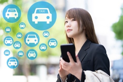 配車アプリを使ってタクシーを呼ぶ女性