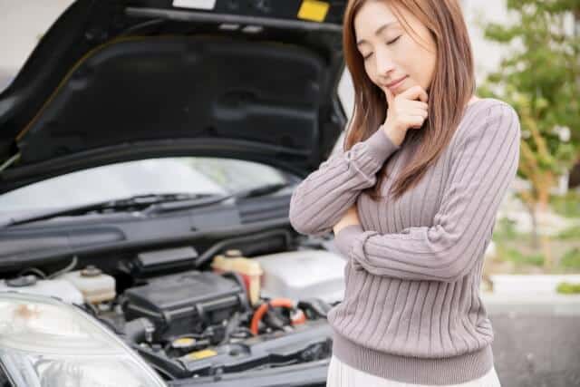 バッテリーが上がって苦慮する女性ドライバー